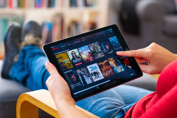 Woman using tablet computer and looking an online streaming platform. The tablet pc is an iPad Air 2, developed by Apple Inc.