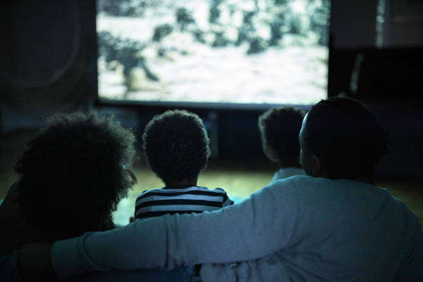Rear view of relaxed African American family watching a movie in the living room.